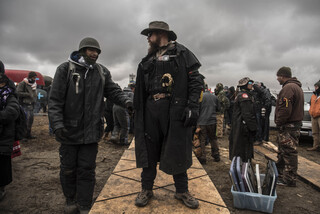 Thelonius stands watch as water protectors build a bridge comprised of planks and foam boards Thanksgiving Day. They built the bridge to travel across part of the river to Turtle Island, a sacred burial ground recently overtaken by police.